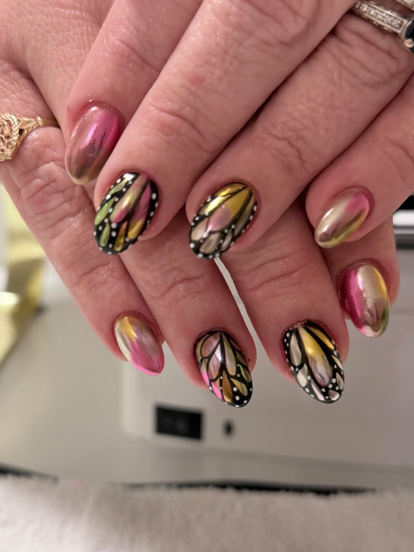 Pink and gold chrome nails with hand-painted monarch butterfly wings and white dots